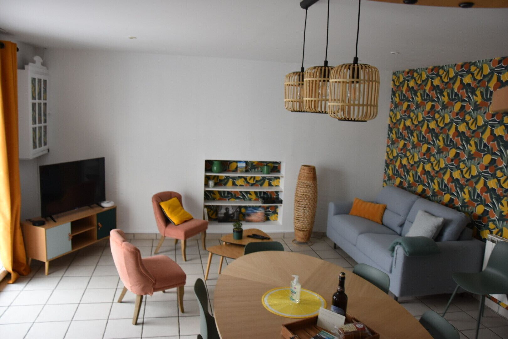 Ein modernes Wohnzimmer mit einer Couch, Sesseln, einem Couchtisch, einem Fernseher und einem Bücherregal.