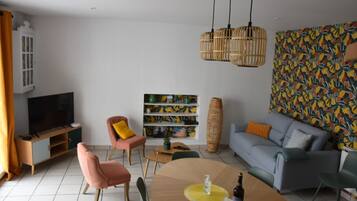 Ein modernes Wohnzimmer mit einer Couch, Sesseln, einem Couchtisch, einem Fernseher und einem Bücherregal.