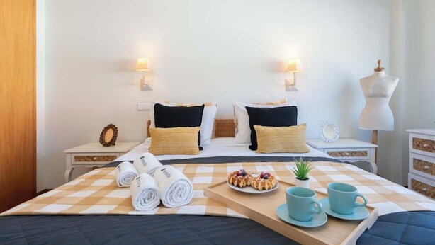 Ett välordnat hotellrum med en säng, två sängbord, en lampa och en liten växt.