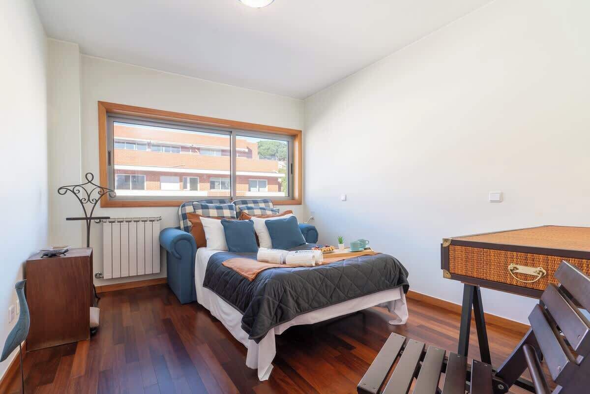 Ein Schlafzimmer mit einem Bett, einem Fenster, einer Heizung, einem Schreibtisch und einem Stuhl.