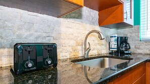 A kitchen with a granite countertop, a stainless steel sink, a coffee maker, and a toaster. - Lazy Livin 6 · Pool 50 Ft Away · 2-Min Beach (Bradenton Beach)