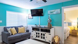 A living room with a grey sofa, white entertainment unit, and a ceiling fan. - Lazy Livin 6 · Pool 50 Ft Away · 2-Min Beach (Bradenton Beach)