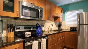 A modern kitchen with wooden cabinets, stainless steel appliances, a granite countertop, and a built-in oven. - Lazy Livin 6 · Pool 50 Ft Away · 2-Min Beach (Bradenton Beach)