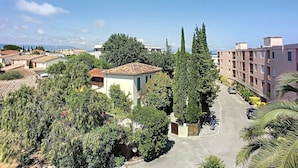 A residential area with a mix of single and multi-story buildings, a clear sky, and a road with parked cars. - (029) L'entre deux à 4 (Antibes)