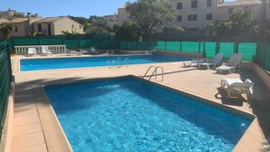 A rectangular swimming pool with clear blue water, surrounded by a tiled deck. There are several white lounge chairs and a small table on the deck. - (029) L'entre deux à 4 (Antibes)