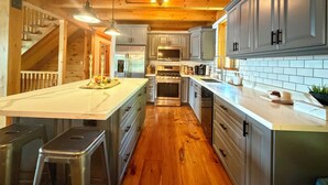 Une cuisine moderne avec des poutres en bois, des appareils en acier inoxydable et un grand îlot central.