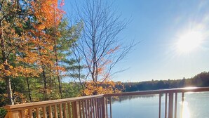 Une terrasse en bois avec un jacuzzi et vue sur le lac.