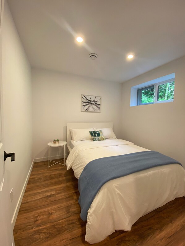 Una camera da letto con un letto, un comodino, una finestra e una lampada a soffitto.