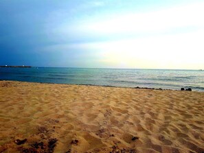 Ein sandiger Strand mit ruhiger See und einer entfernten Küste.