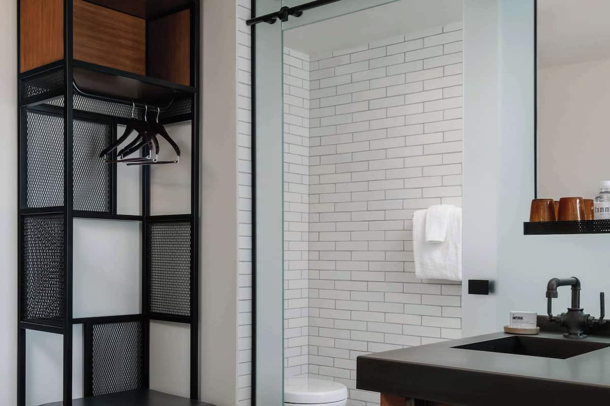 Une salle de bain avec un meuble-lavabo en bois, une cabine de douche en verre et une étagère en métal.