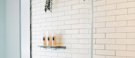 A shower area with white brick walls, a glass door, and a showerhead.