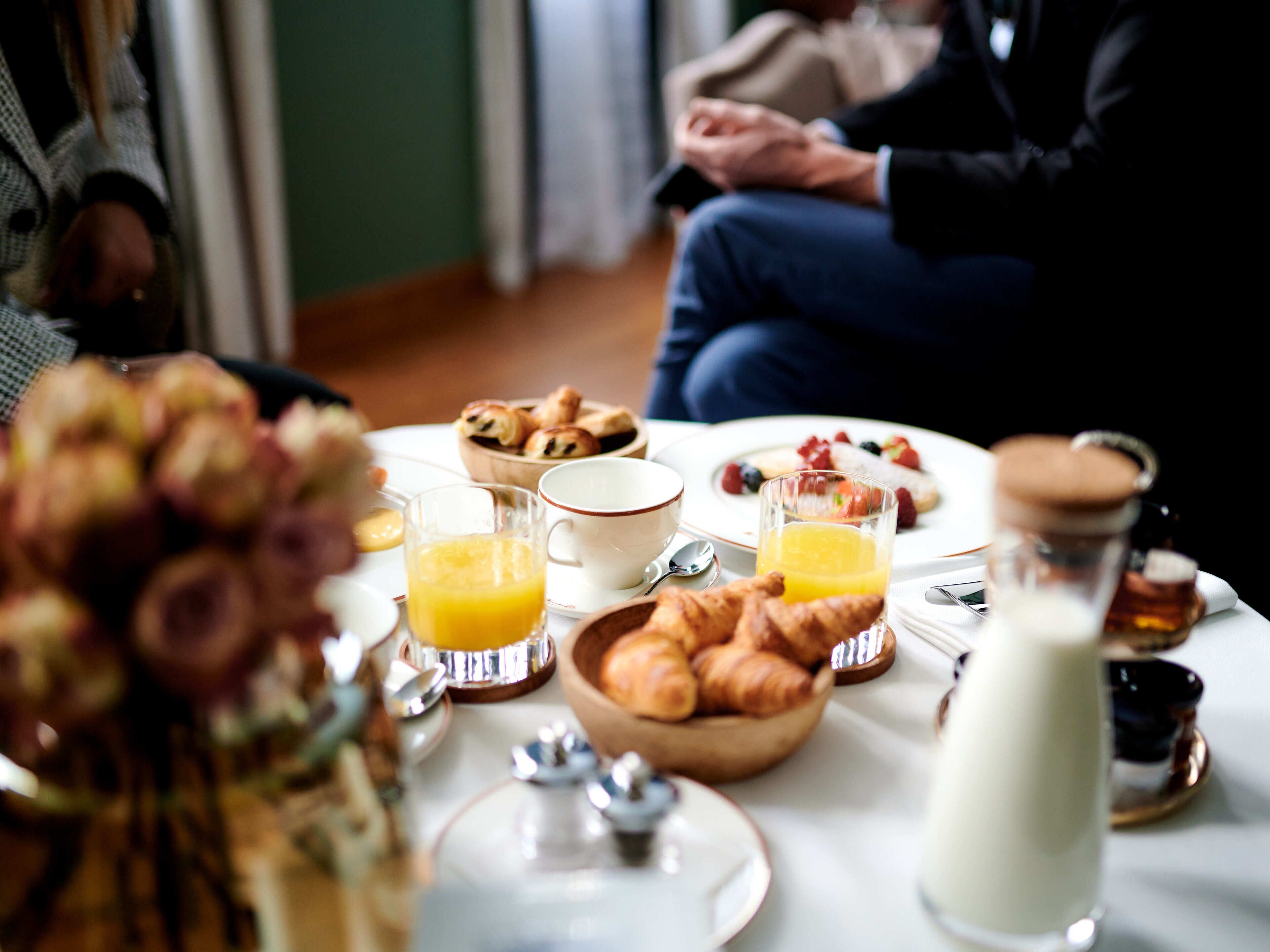Morgenmad med croissanter, frugt og appelsinjuice på et bord.