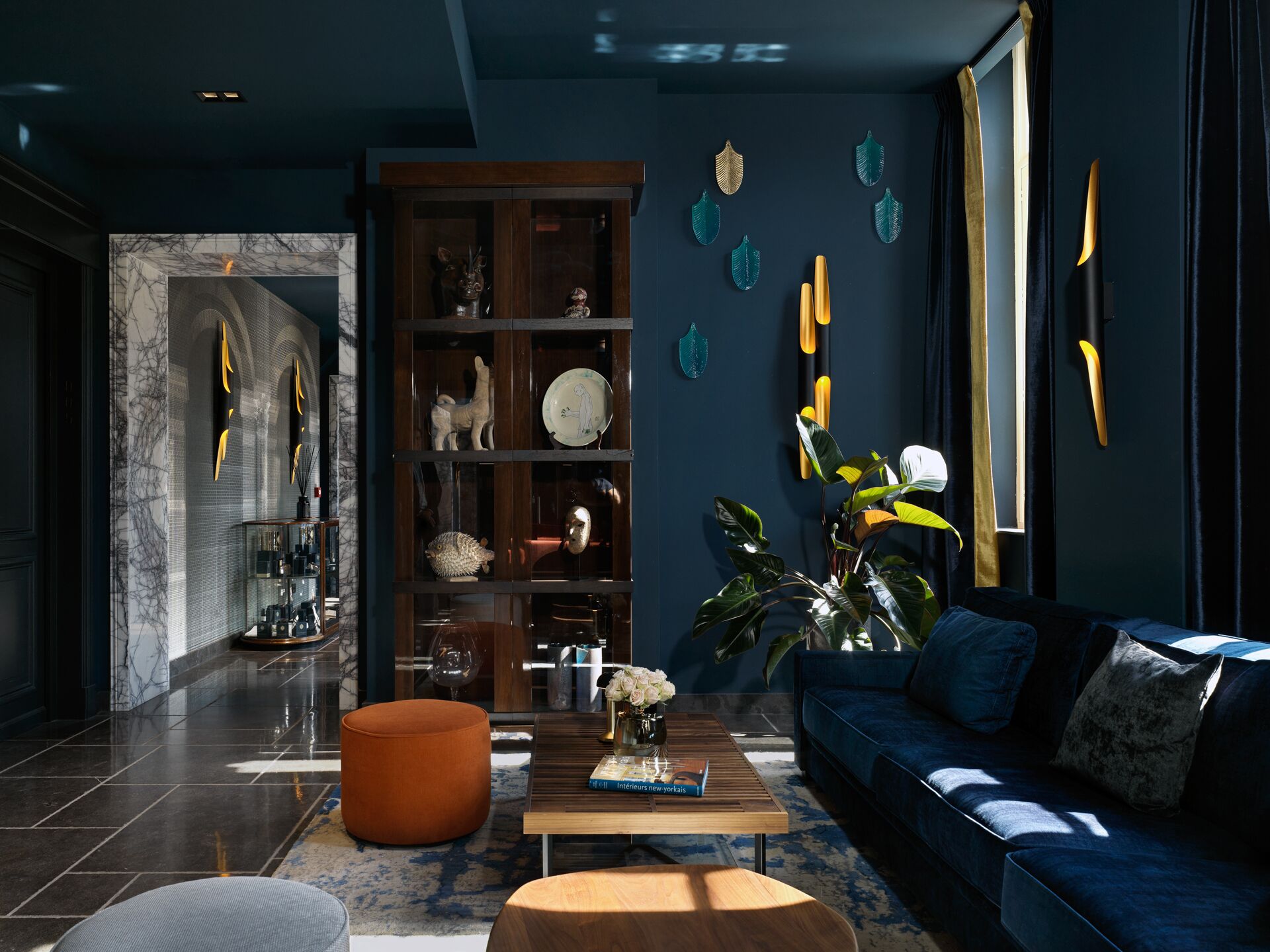 A modern living room with a blue sofa, a coffee table, and a bookshelf.