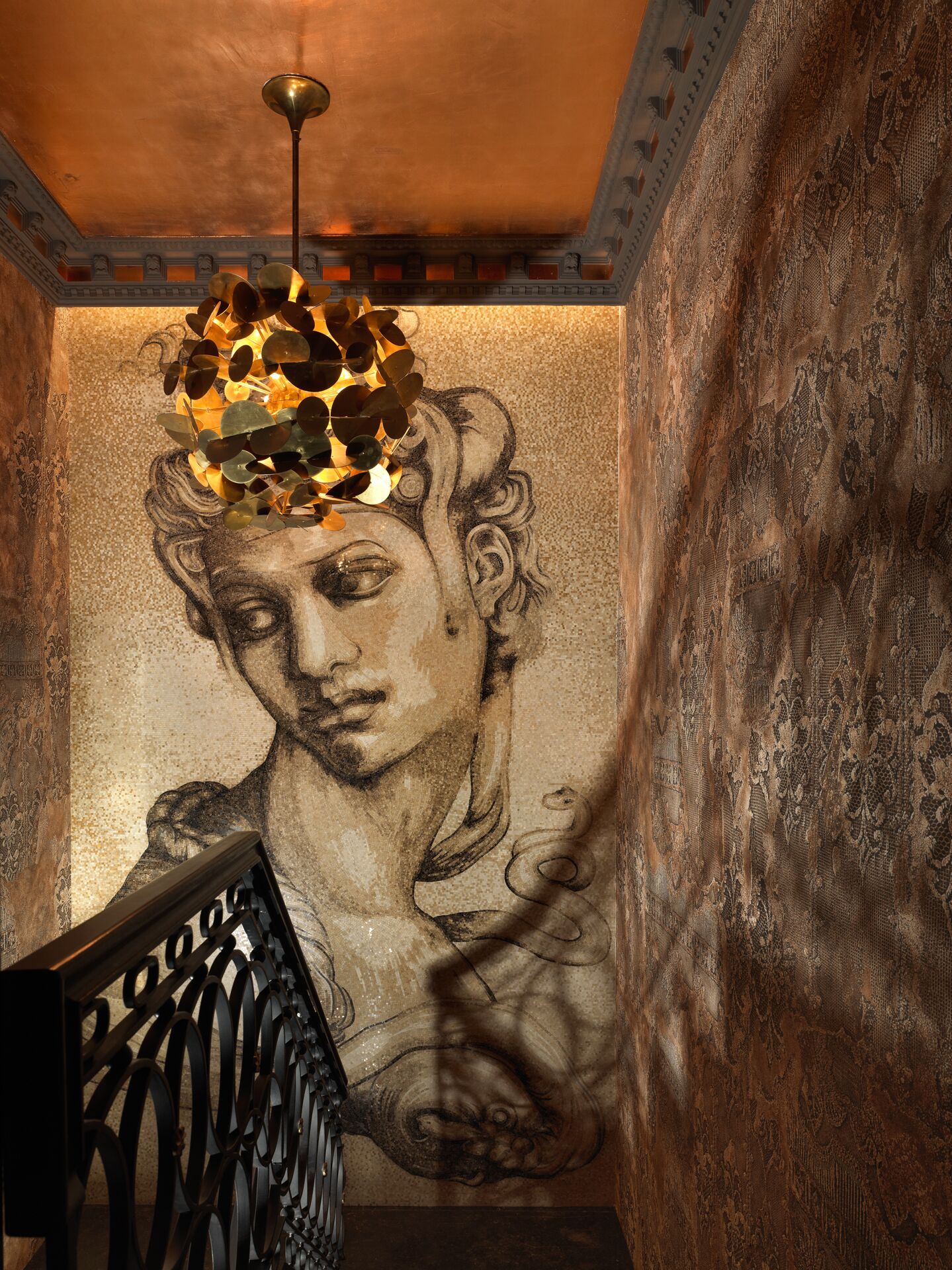Een trap met een decoratieve metalen balustrade en een muurschildering met een klassiek beeldhouwwerk.