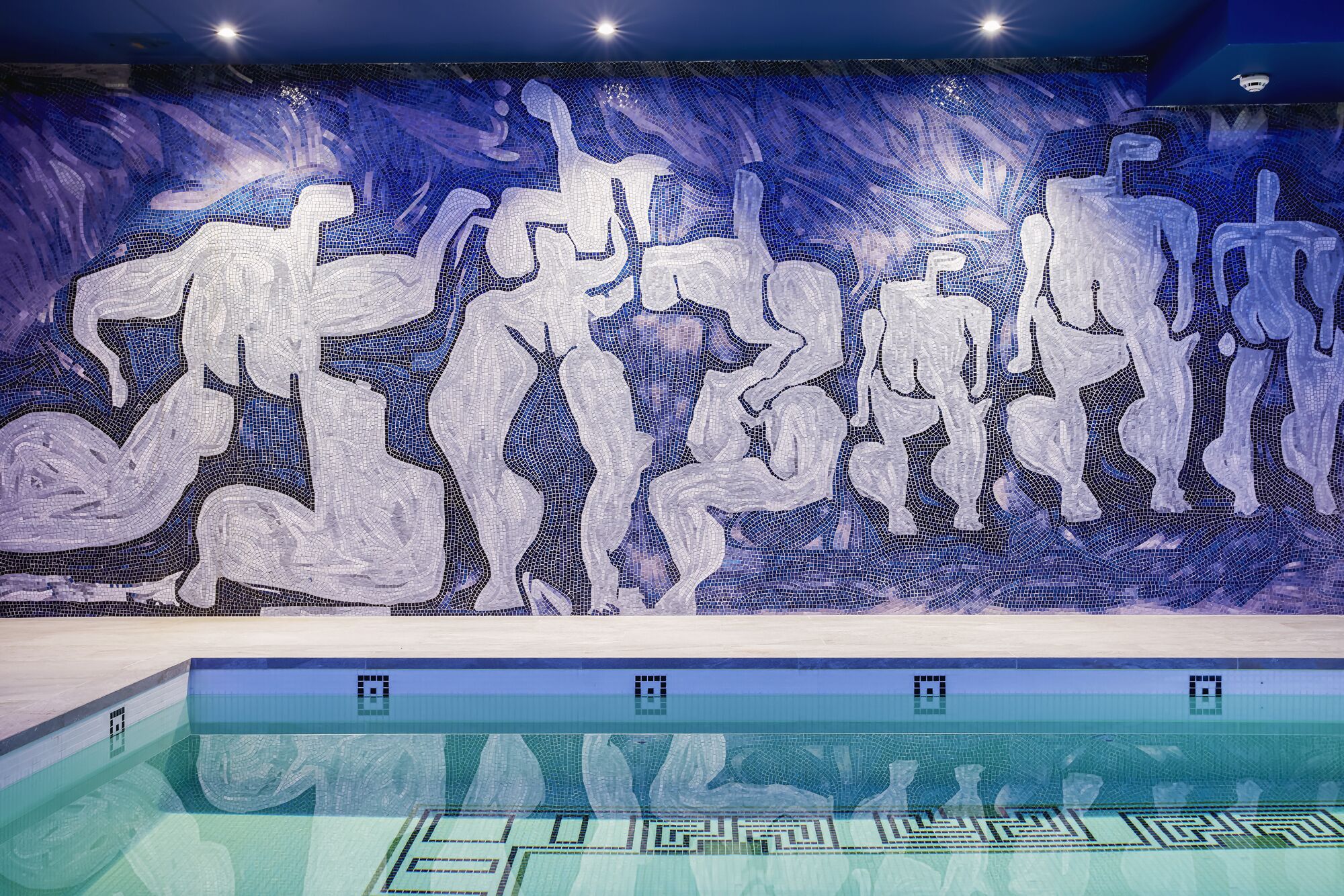 Ein Swimmingpool mit einem Mosaikbild an der Wand.