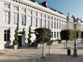 En historisk bygning med symmetrisk arkitektur, store vinduer og en belagt gårdsplads.