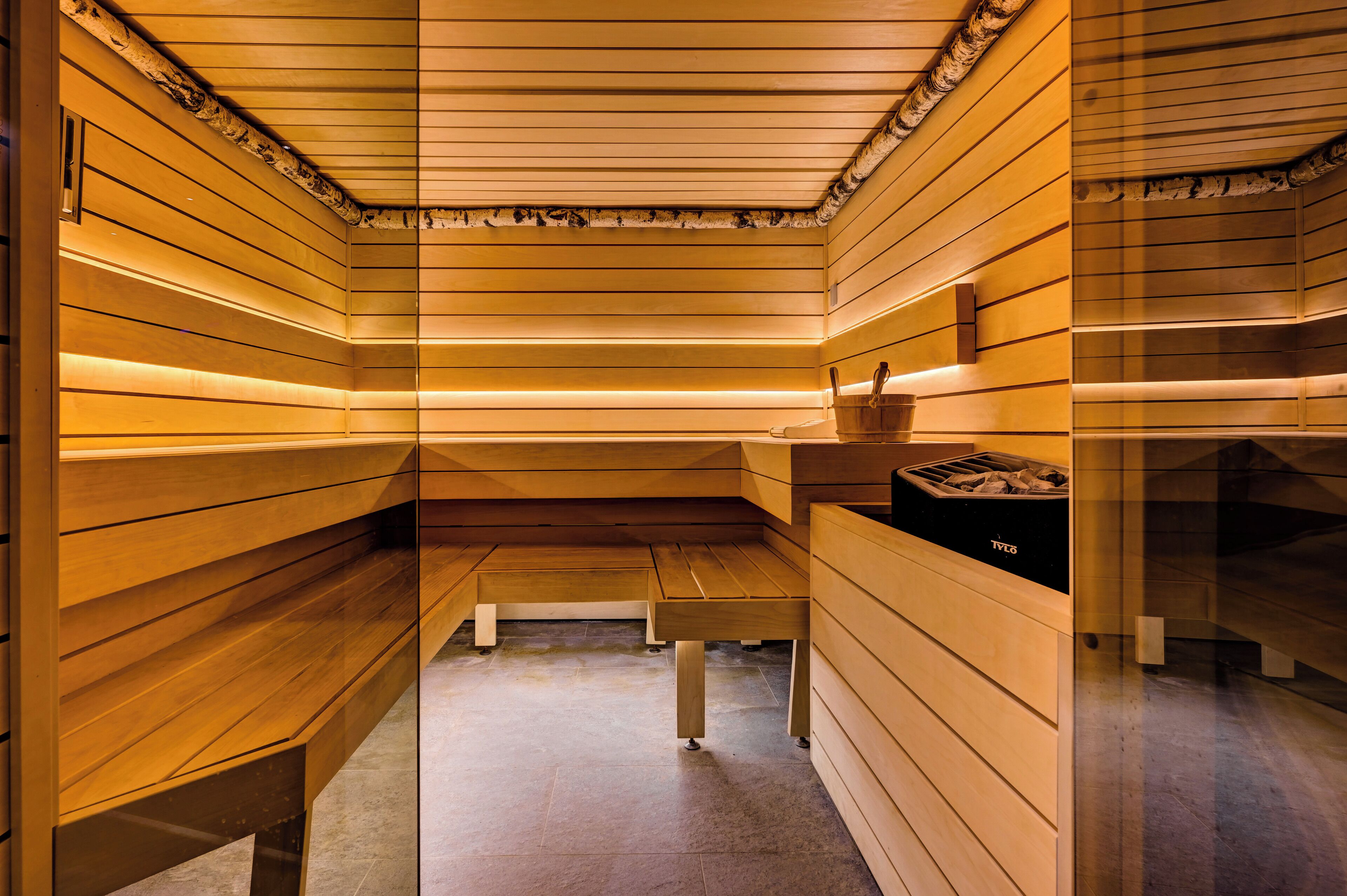 Uma sauna com paredes e bancos de madeira, uma mesa e uma lixeira.