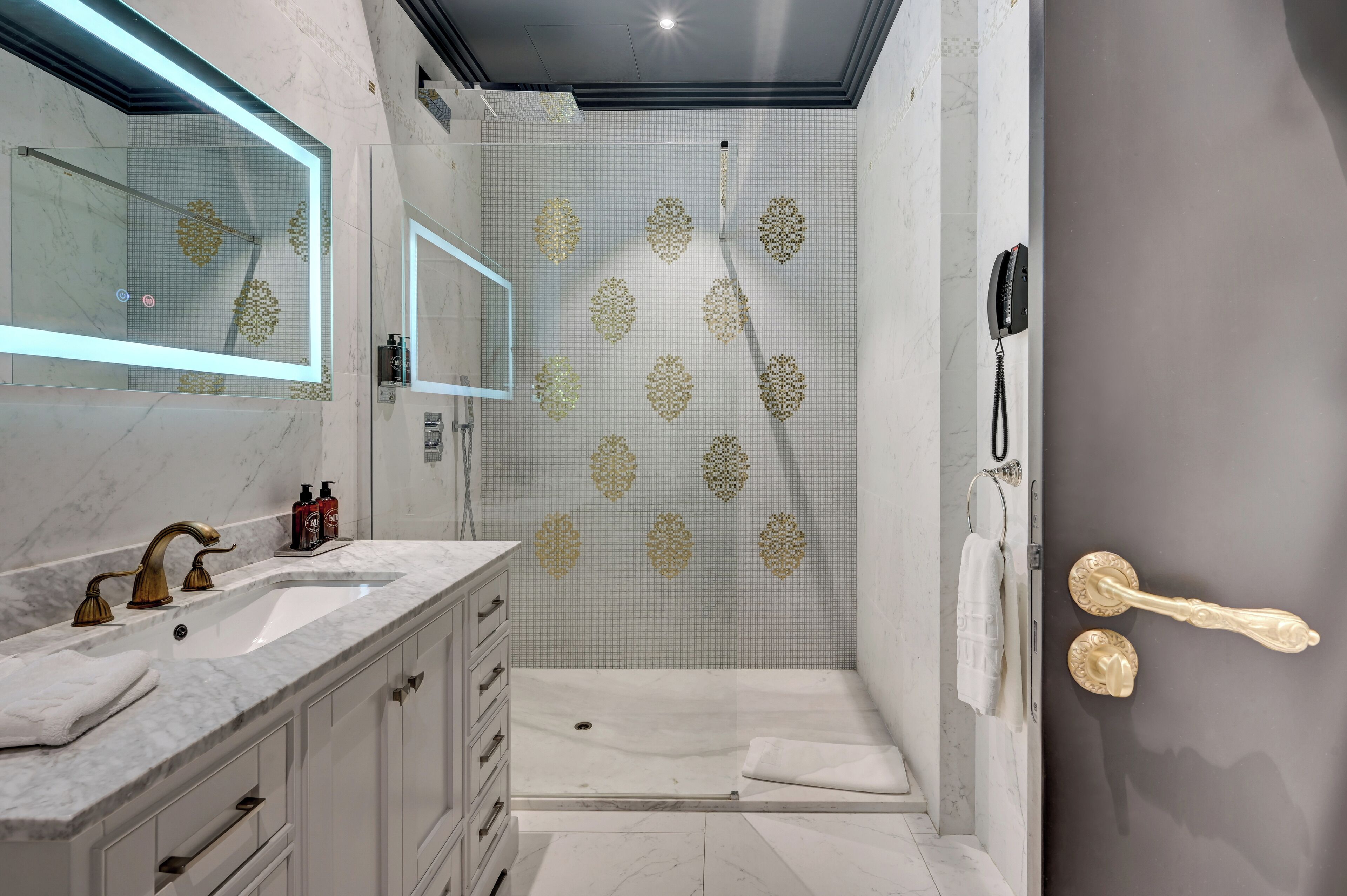A modern bathroom with a large mirror, a vanity with a sink, and a shower area with a glass door.