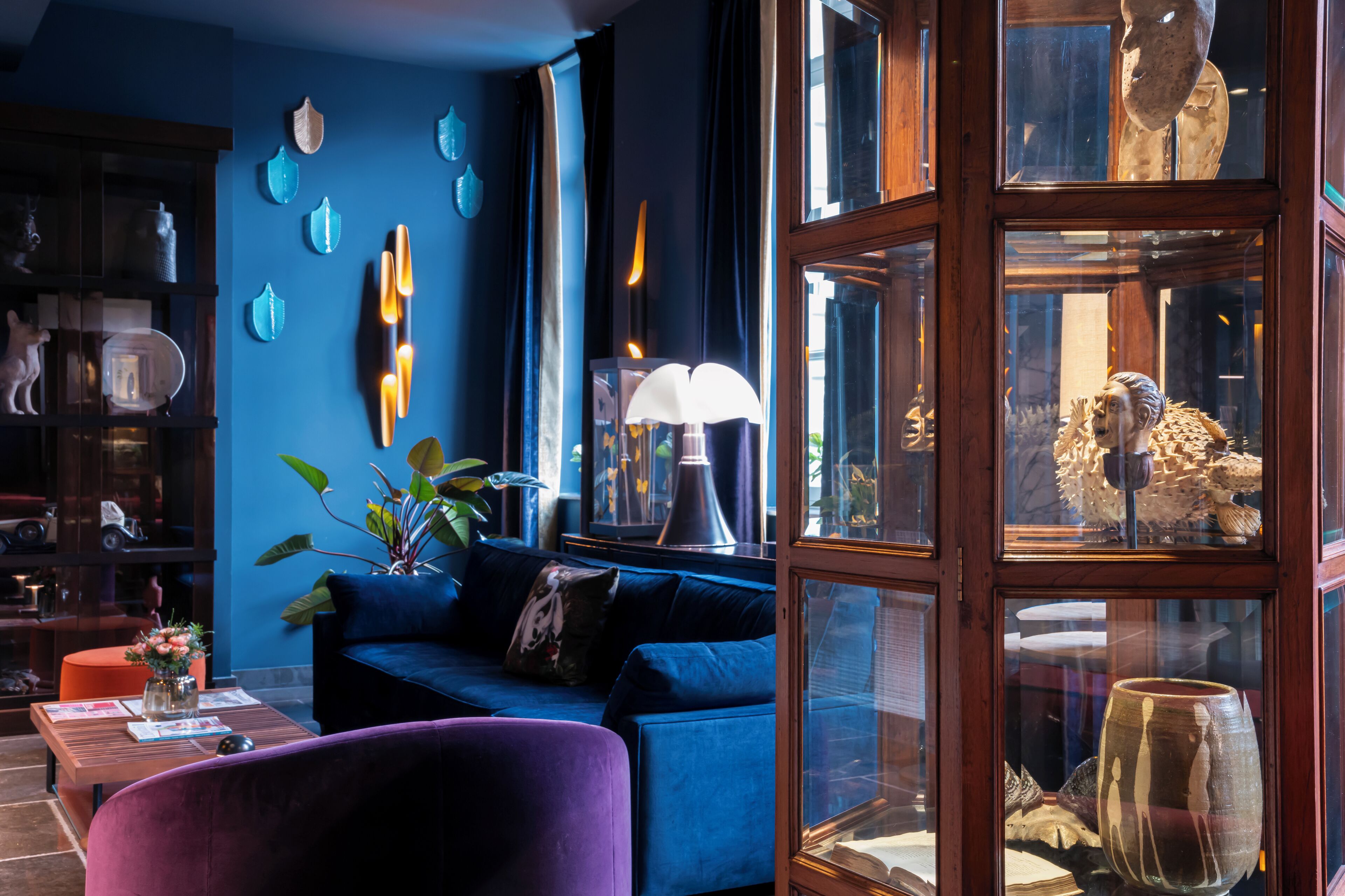 Un salon moderne avec un canapé bleu, une table basse en bois et des objets décoratifs accrochés aux murs.