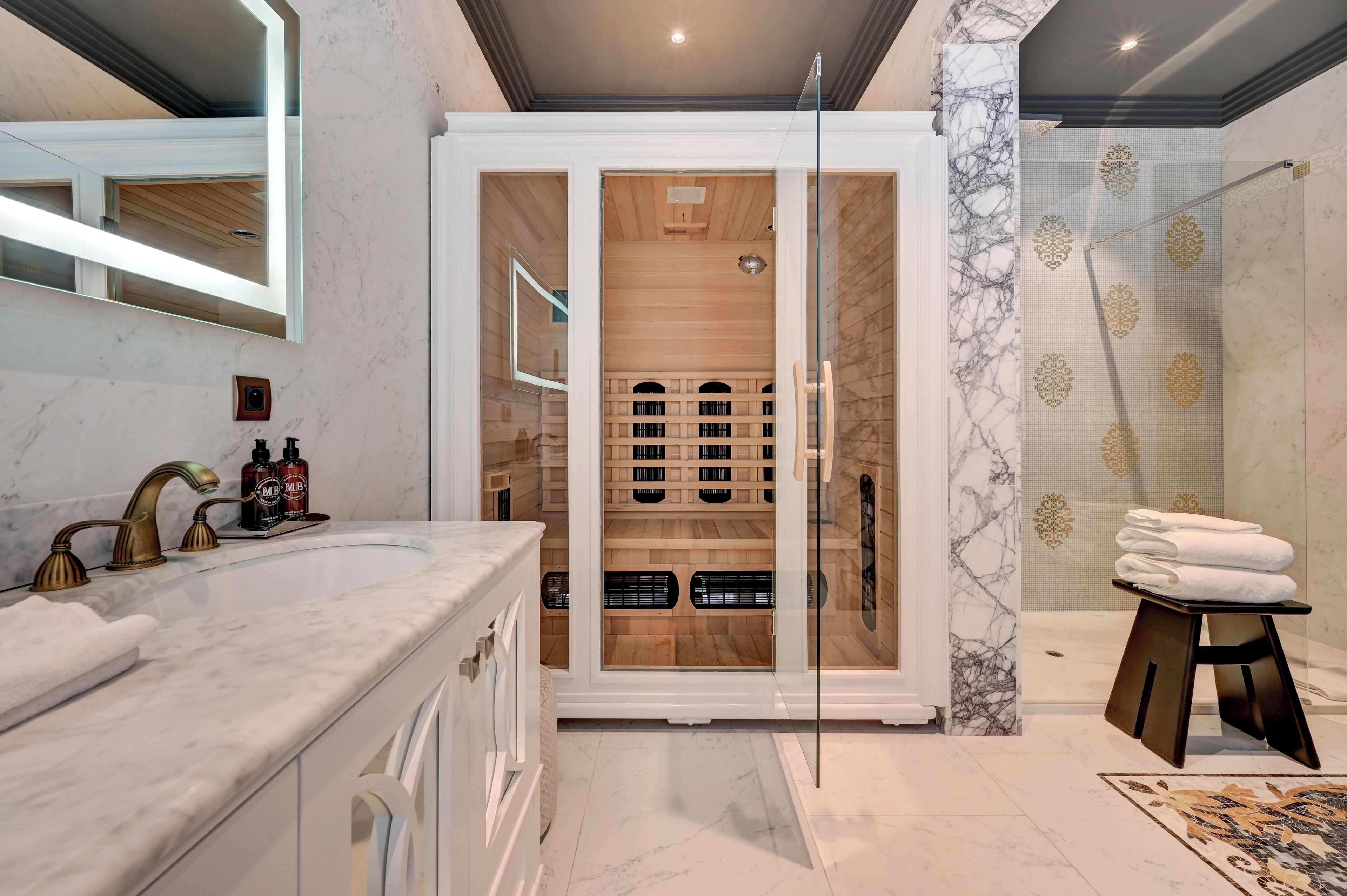 Ein modernes Badezimmer mit Marmorwaschtisch, einer Duschkabine aus Glas und einem Holzschrank.