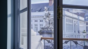 A view from a window overlooking a statue and a classical building facade.