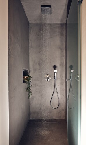 Een moderne douche met regendouche, handdouche en een douchecabine met glazen wanden.