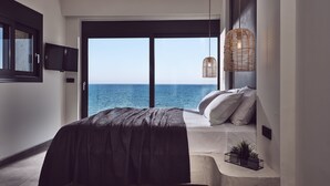 A bedroom with a large bed, a TV, a view of the sea, and wicker lighting. - Sea Front LaMer Villa,Luxury Retreat & Heated Pool (Zakynthos)