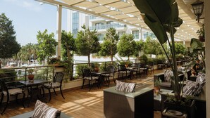 An outdoor patio area with tables and chairs, surrounded by potted plants and a view of a building. - Castival Hotel - All inclusive (Manavgat)