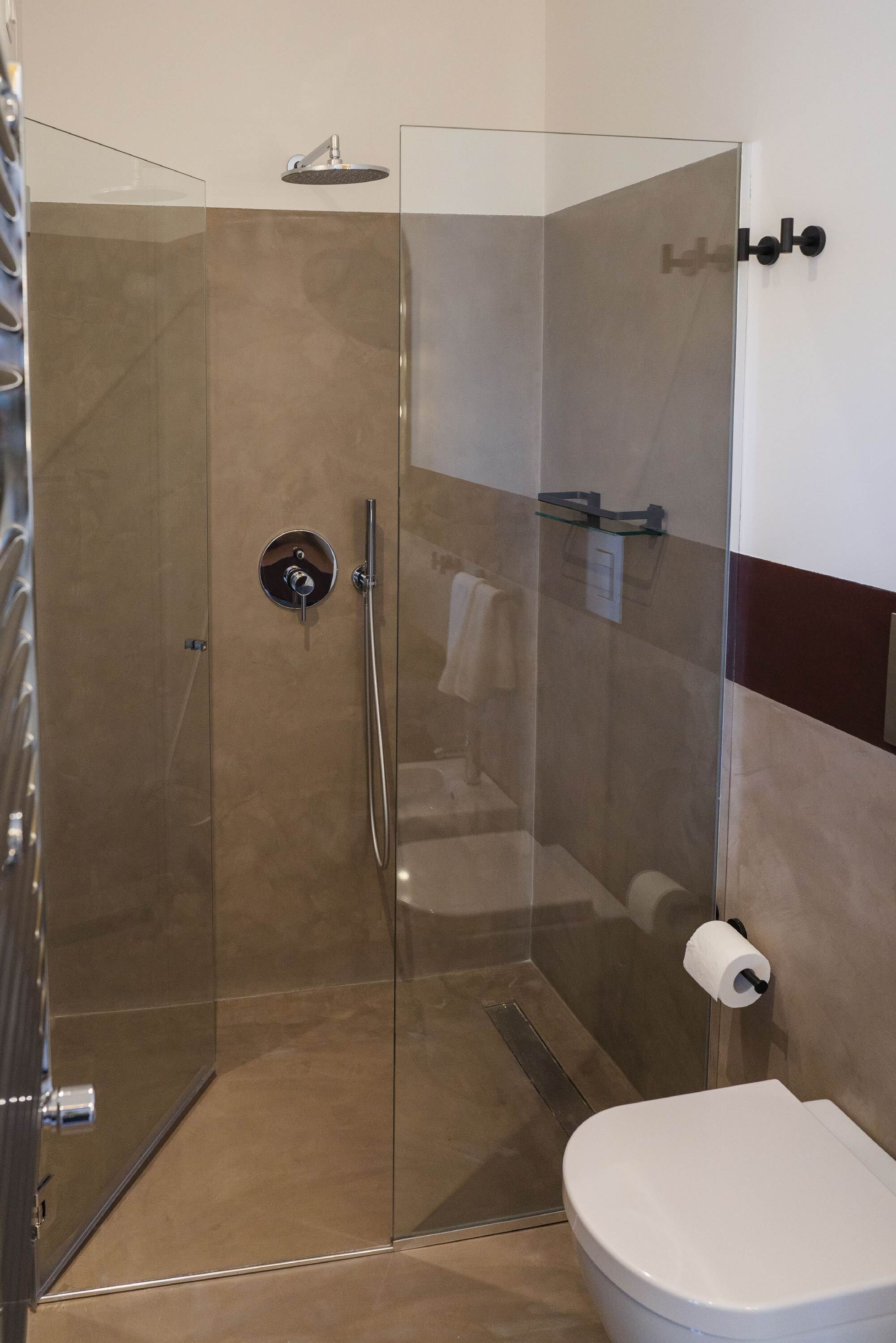 A modern bathroom with a glass-enclosed shower, a toilet, and a towel rack.