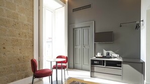 A compact kitchen with a dining area, a TV mounted above the counter, and a door leading to another room. - Ciao Bellini (Naples)
