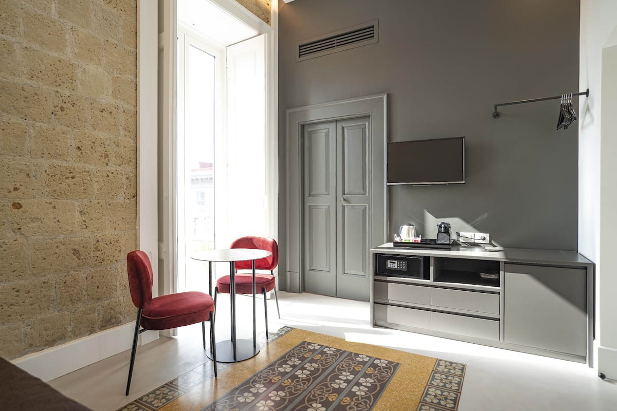 A compact kitchen with a dining area, a TV mounted above the counter, and a door leading to another room.
