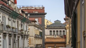 A narrow street with historic buildings, a central archway, and a bus stop. - Ciao Bellini (Naples)