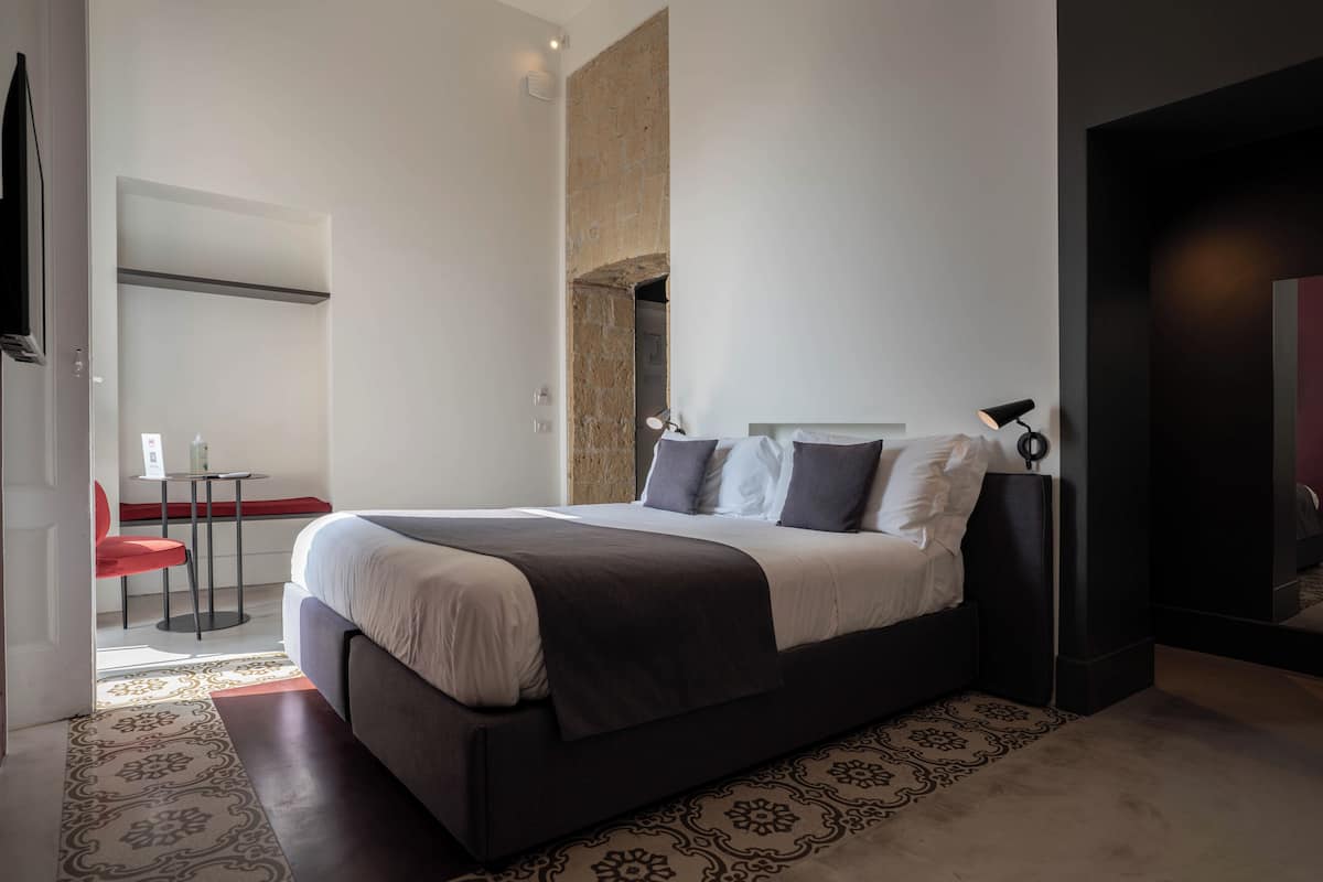 A modern bedroom with a large bed, a small table, and a red chair.