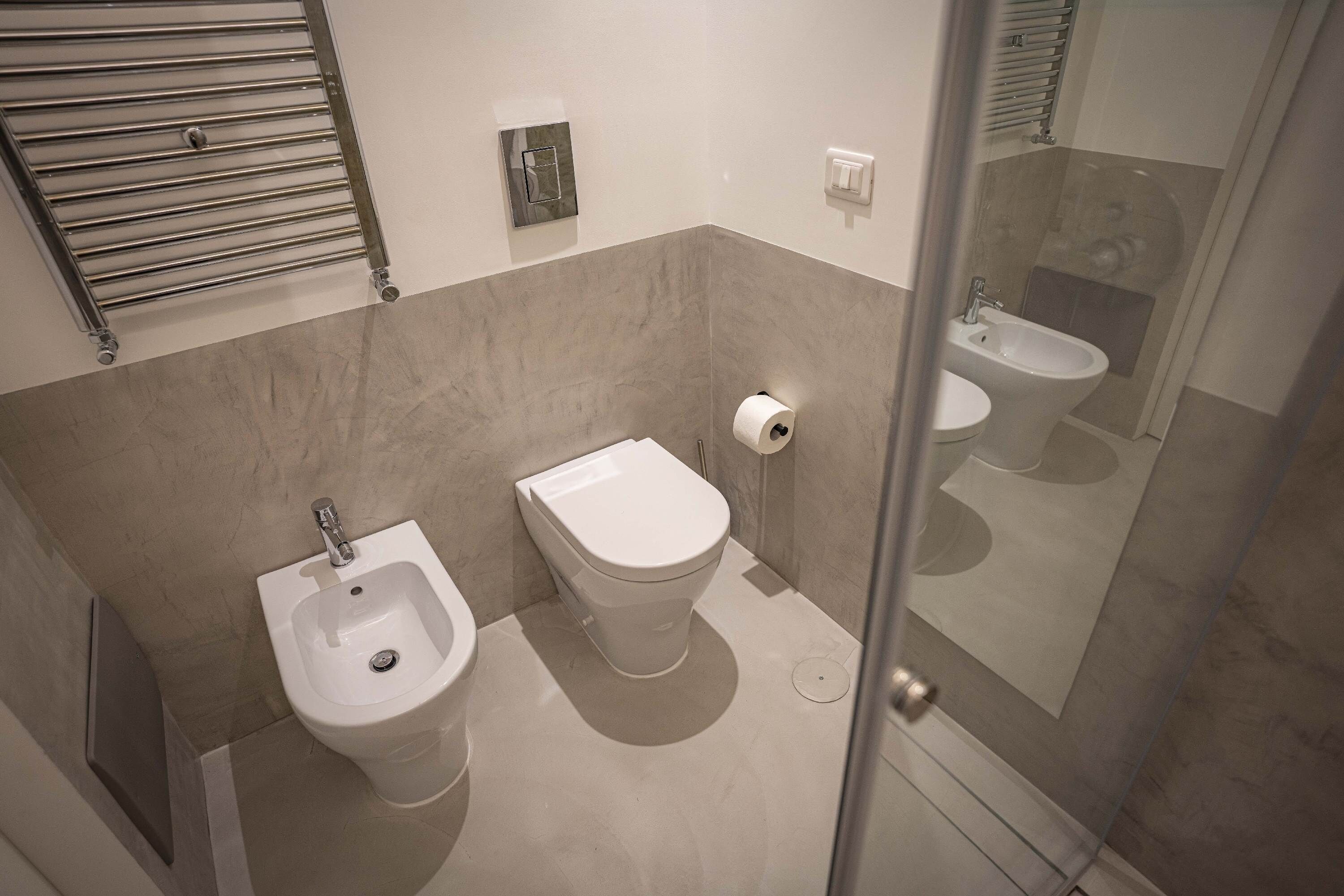 A modern bathroom with a bidet, toilet, and a glass-enclosed shower area.