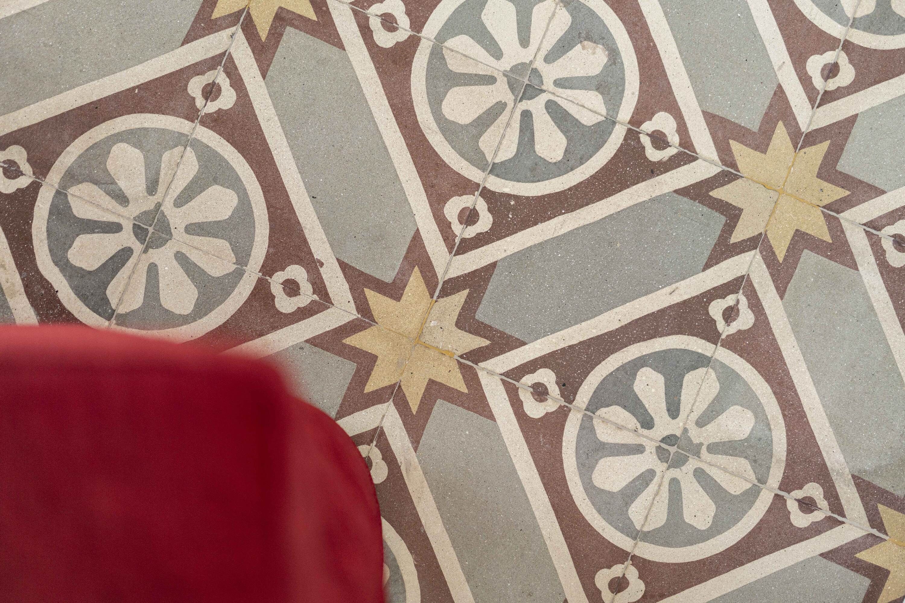 A close-up of a patterned floor with geometric shapes and floral motifs.