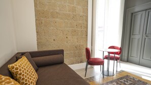 A living room with a brown sofa, red chairs, a patterned rug, and a stone wall. - Ciao Bellini (Naples)
