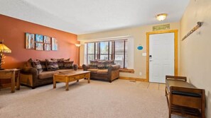 A living room with two sofas, a coffee table, a lamp, and a door.