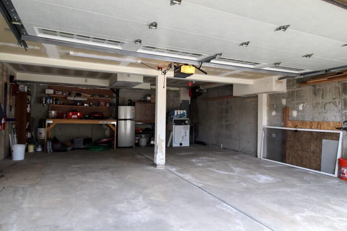 A garage with a concrete floor, a workbench, and various tools and equipment.