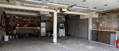 A garage with a concrete floor, a workbench, and various tools and equipment.