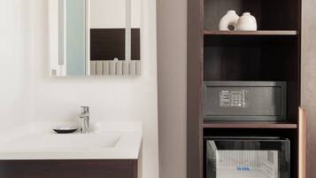 A modern bathroom with a white sink, dark wooden vanity, and a built-in shelving unit with decorative items and appliances.