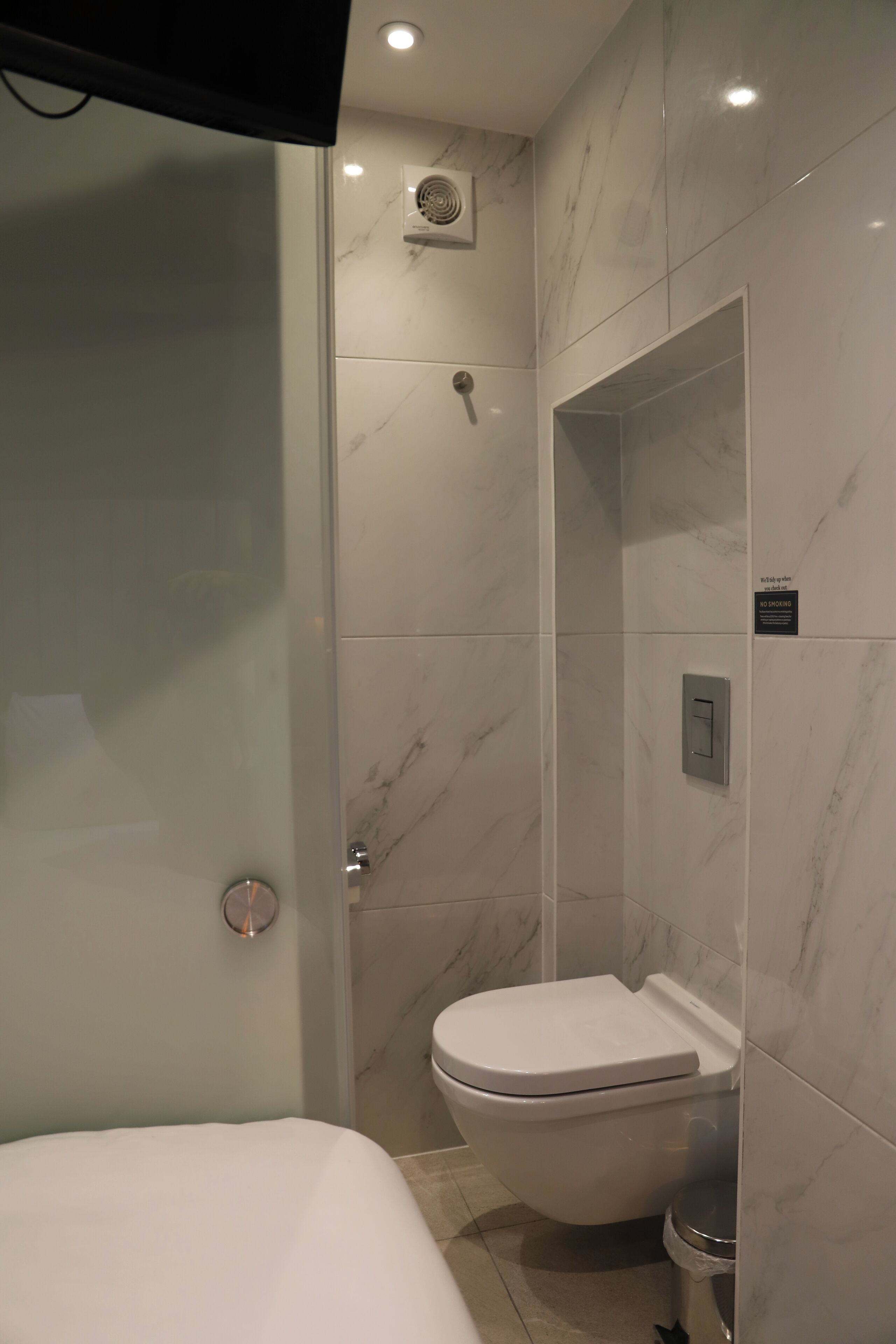 A modern bathroom with a glass-enclosed shower, a toilet, and a control panel.