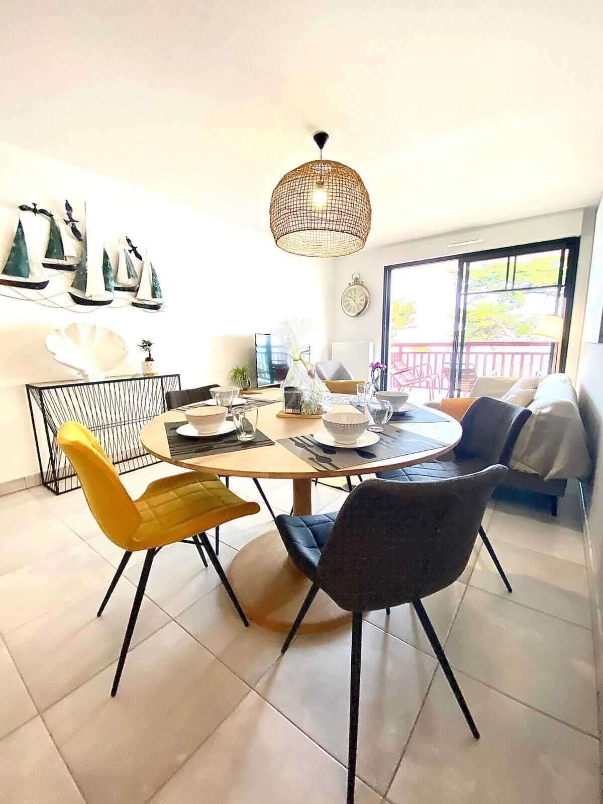A dining area with a round table, chairs, and a hanging light fixture.
