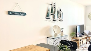 A modern living room with a wooden table, a potted plant, and a sign reading "La Grande Plage". - SEAFRONT APARTMENT VAL ANDRE ALL INCLUSIVE FOR 5 PEOPLE (Pléneuf-Val-André)