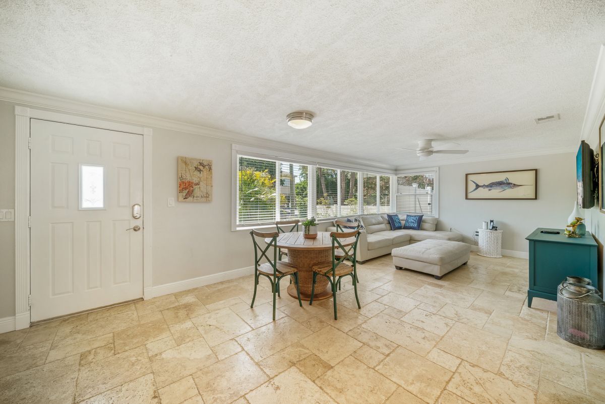 A spacious living area with a dining table, a sofa, and a ceiling fan.