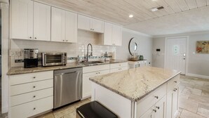 A modern kitchen with white cabinets, stainless steel appliances, and a granite countertop.