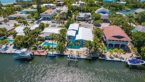 An aerial view of a coastal residential area with houses, a marina, and a swimming pool.
