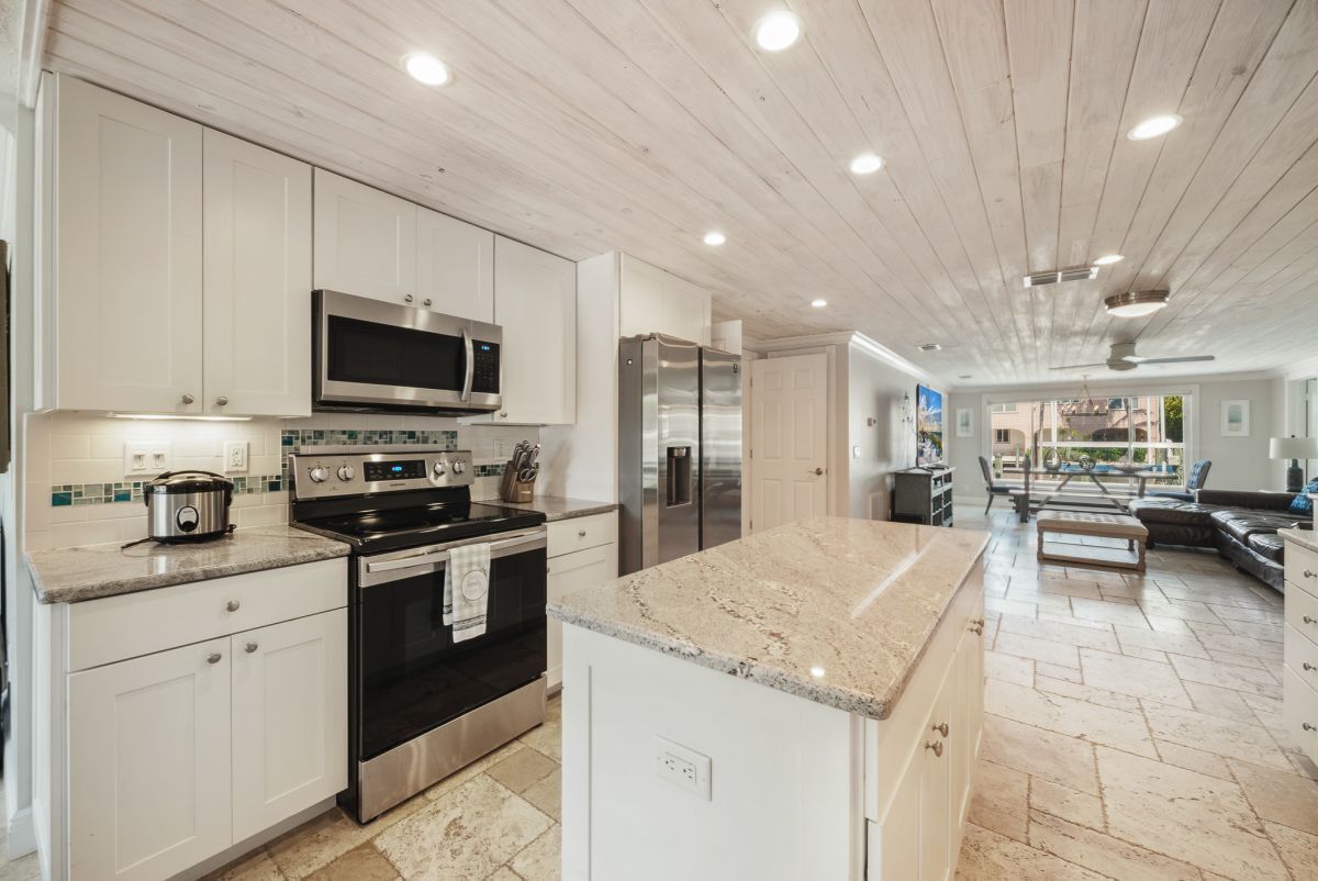 A modern kitchen with white cabinets, stainless steel appliances, and a granite countertop.