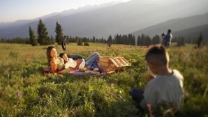A group of people relaxing on a blanket in a grassy field with mountains in the background. - Newly Remodeled Condo Wren 201 with Creekside Views of Vail Mountain by RedAwning (Vail)