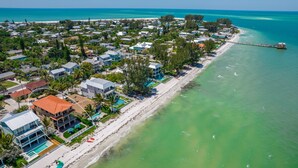 An aerial view of a coastal residential area with houses, a beach, and a pier. - Bella Vista: Bay front with gorgeous views and outdoor living space. (Anna Maria)