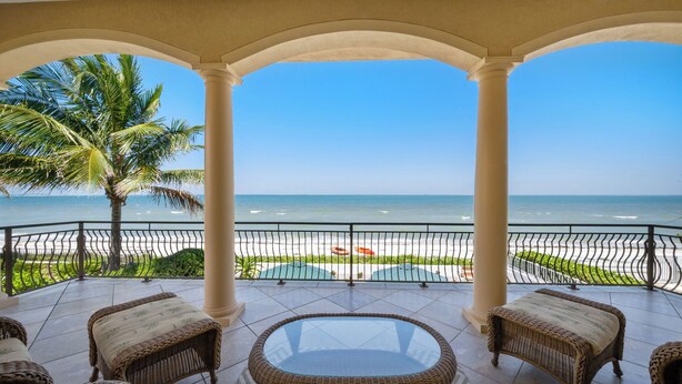 A covered balcony with wicker furniture, a glass table, and a view of the beach and ocean. - Bella Vista: Bay front with gorgeous views and outdoor living space. (Anna Maria)
